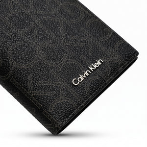 Macro close-up studio shot focusing on the round silver metal CK hardware logo and vertical stitching details over black smooth genuine leather
