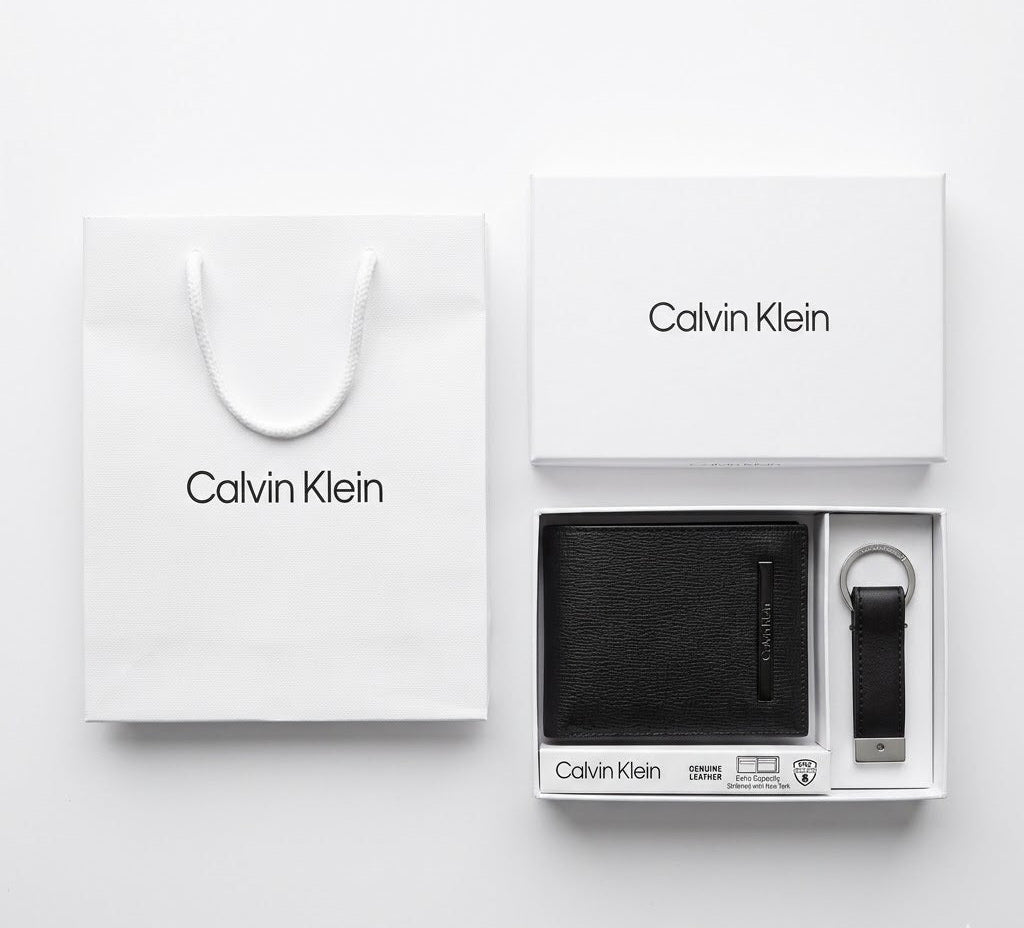 Full premium packaging presentation of the Calvin Klein mirror original smooth black leather wallet and keychain set with its white gift box and matching shopping bag