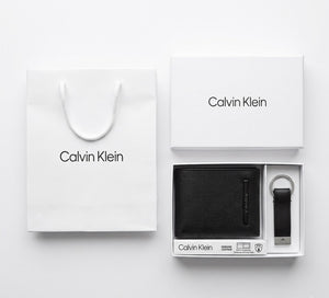 Full premium packaging presentation of the Calvin Klein mirror original smooth black leather wallet and keychain set with its white gift box and matching shopping bag