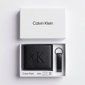 Top-down studio product photography of the Calvin Klein mirror original smooth black leather wallet and keychain set neatly resting inside its open white branded gift box