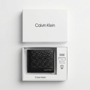Top-down studio product photography of the Calvin Klein mirror original monogram black leather wallet neatly resting inside its open custom white branded gift box
