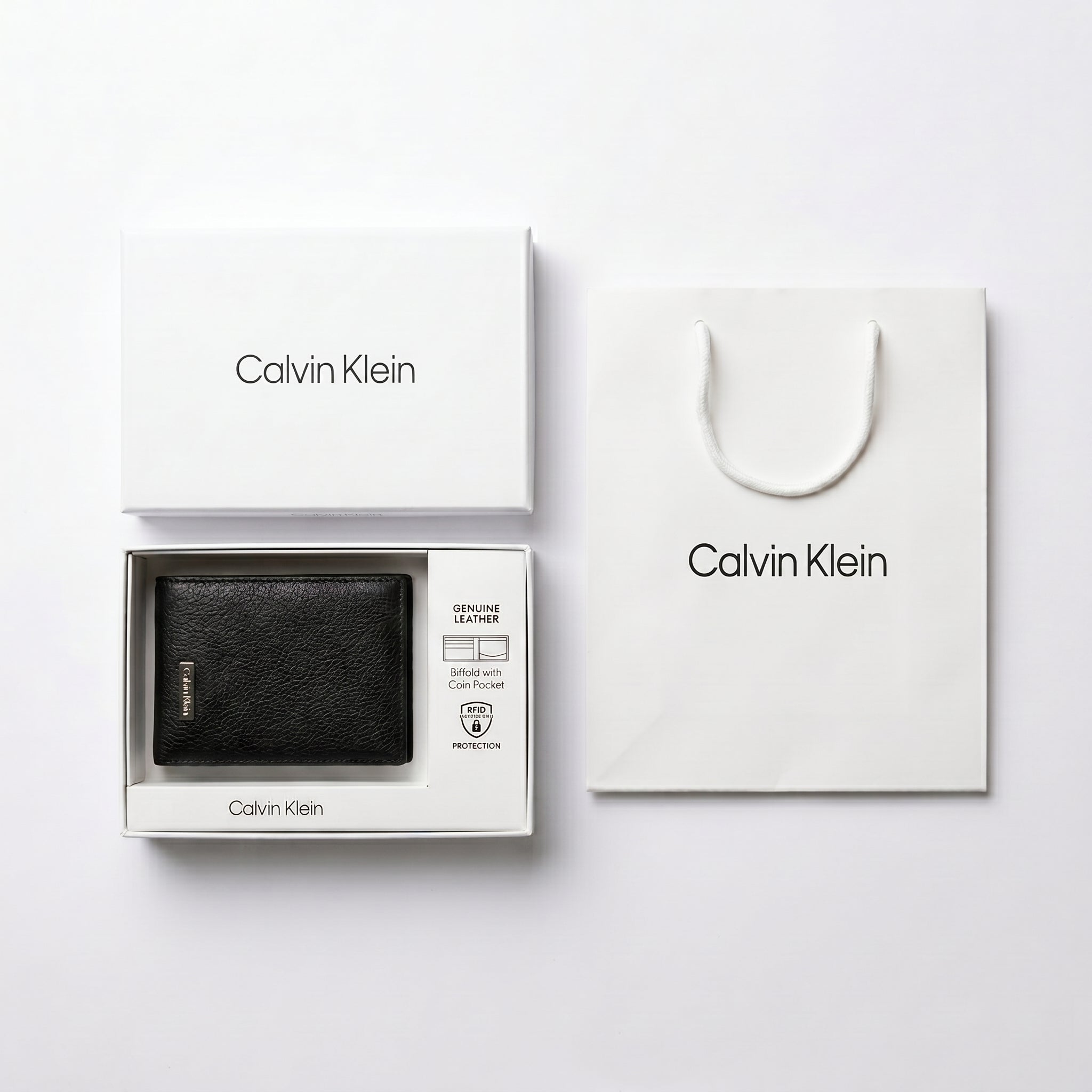 Full premium packaging presentation of the Calvin Klein mirror original pebbled black leather trifold wallet alongside its white gift box and matching shopping bag