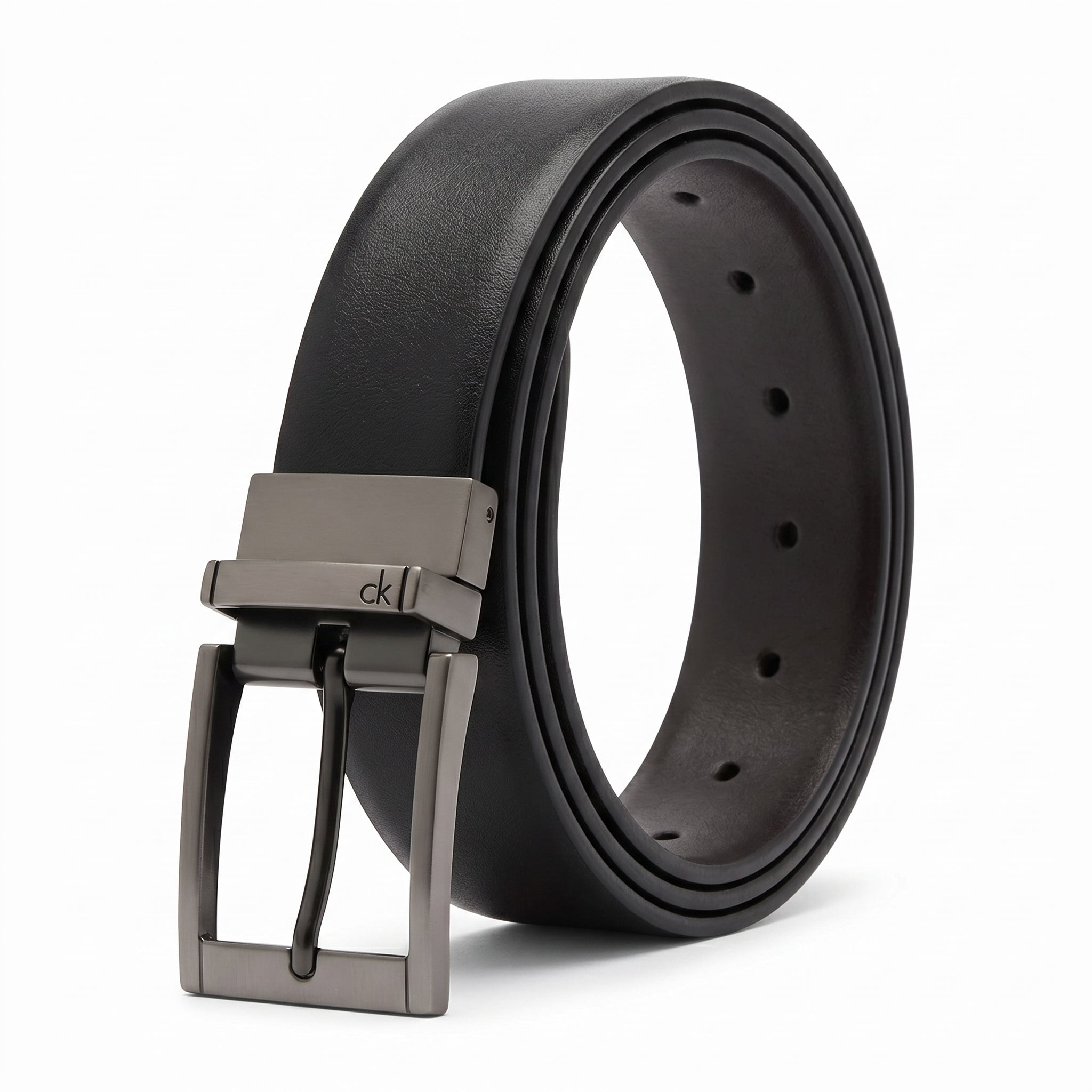 Studio product photograph of the Calvin Klein mirror original reversible leather belt coiled in an oval shape showcasing the smooth black leather and gunmetal buckle