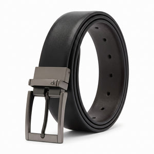 Studio product photograph of the Calvin Klein mirror original reversible leather belt coiled in an oval shape showcasing the smooth black leather and gunmetal buckle