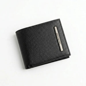 Macro close-up studio shot focusing on the engraved silver metal Calvin Klein logo plate over the black smooth genuine leather surface