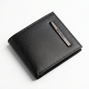 Macro close-up studio shot focusing on the engraved vertical silver metal Calvin Klein logo plate over the scratch-resistant black textured leather surface