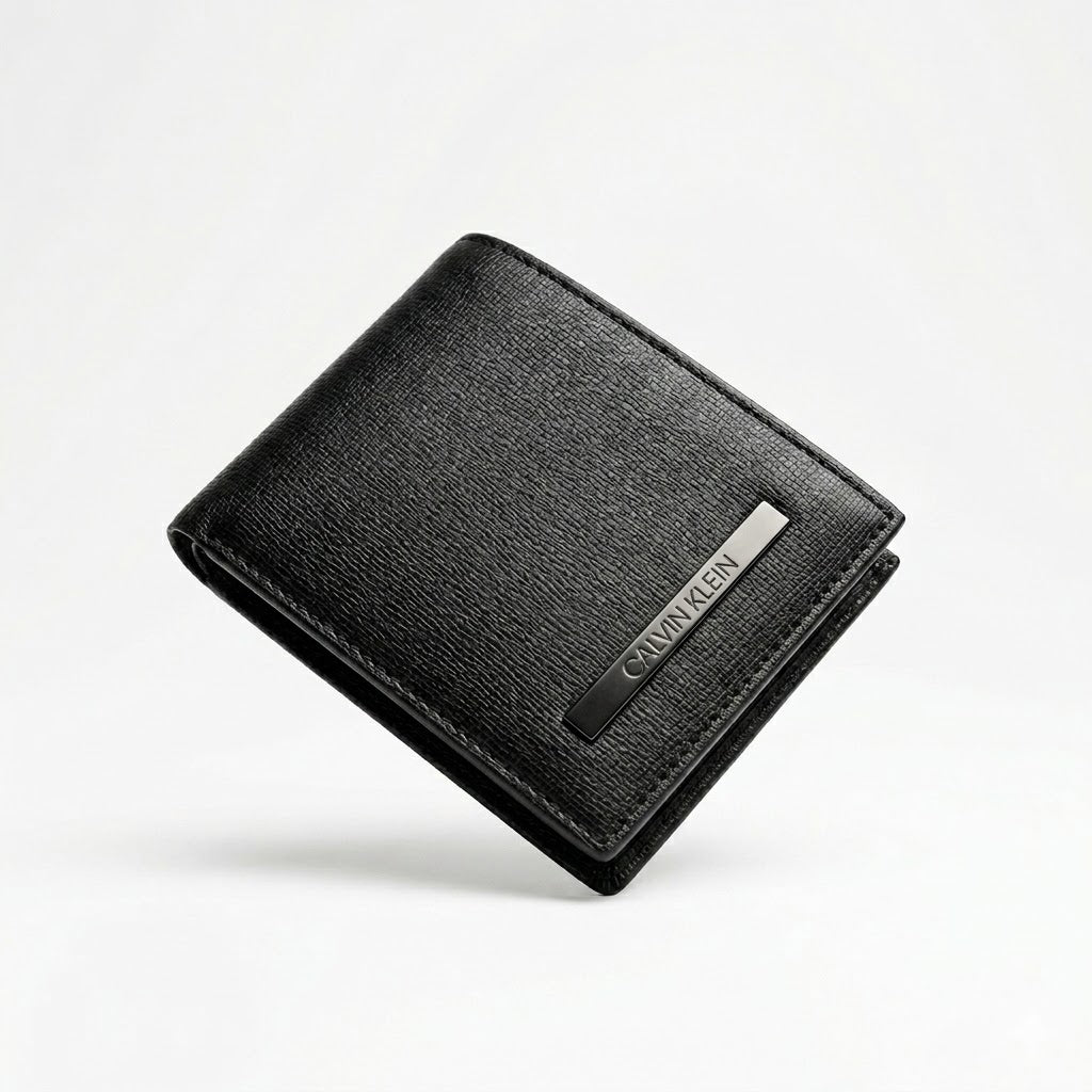 Straight front view product photograph of the Calvin Klein mirror original black leather wallet highlighting the saffiano textured finish and vertical silver metal logo plate