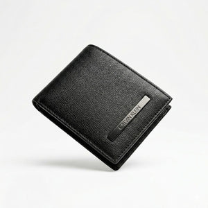 Straight front view product photograph of the Calvin Klein mirror original black leather wallet highlighting the saffiano textured finish and vertical silver metal logo plate