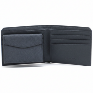 Fully open interior view of a Calvin Klein men's navy blue saffiano leather wallet featuring a snap-button coin pocket on the left and card slots with debossed branding on the right