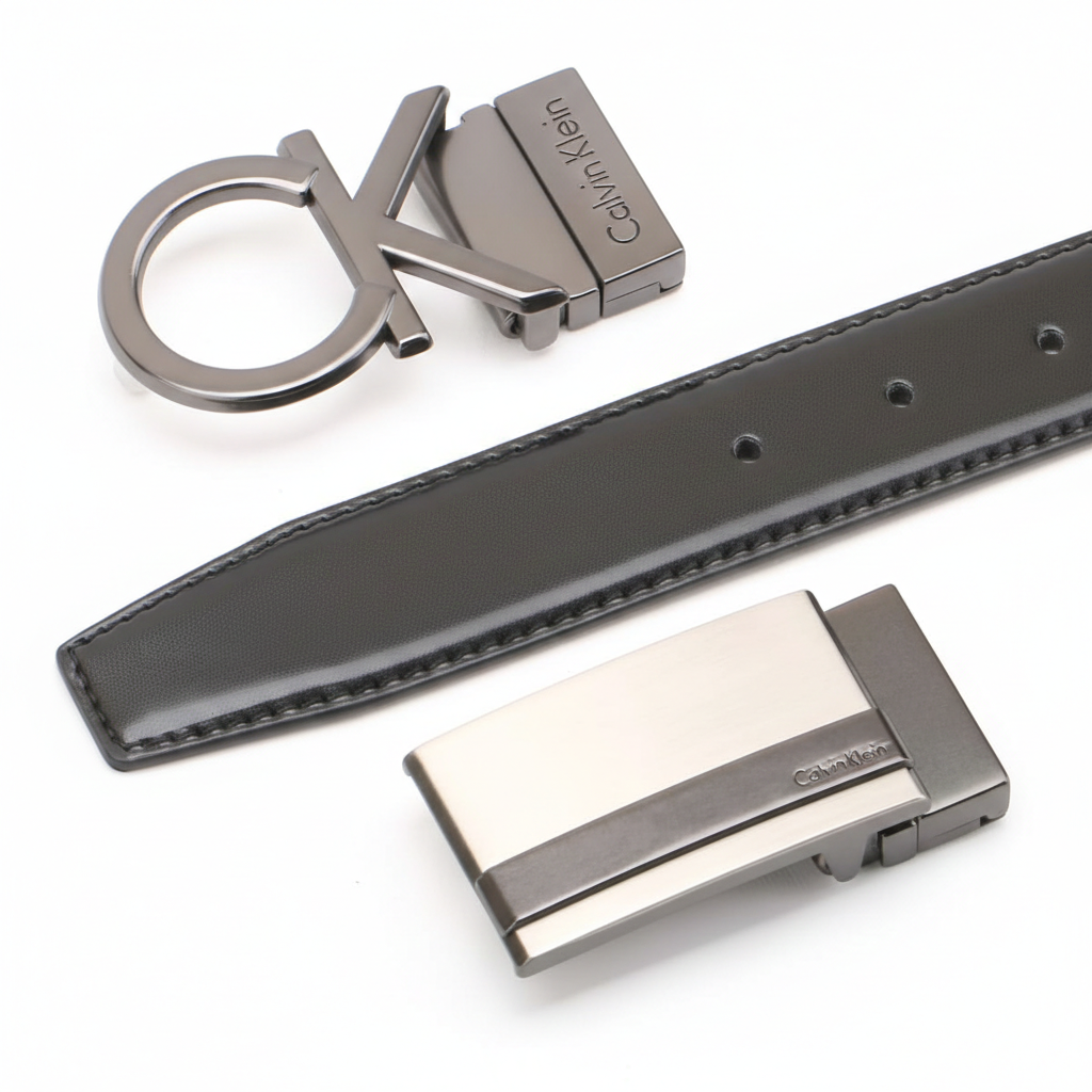 Detailed view of a Calvin Klein black leather belt shown with its two interchangeable designer buckles: a large cK plaque and a sleek rectangular metal buckle