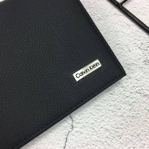 Close up of silver Calvin Klein metal logo plate on black pebbled leather
