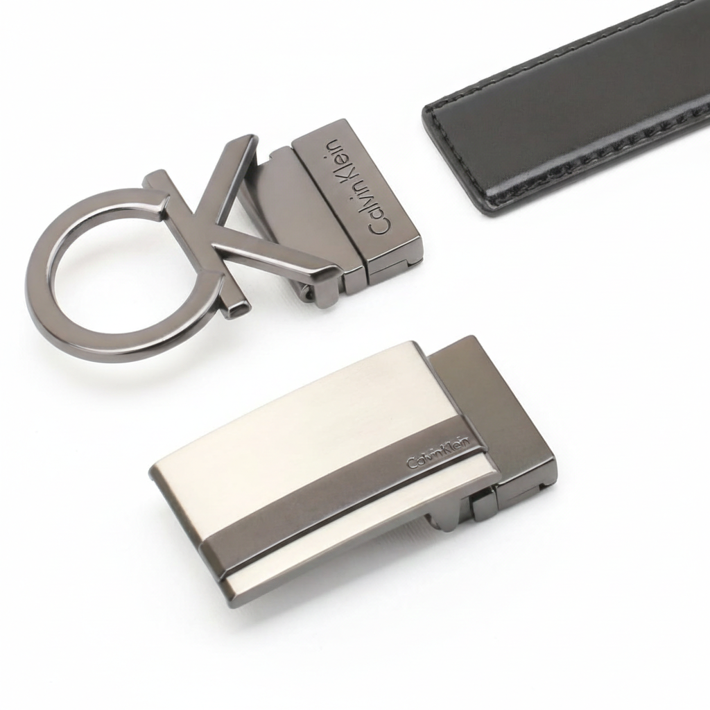 High-detail close-up of the two metal buckles in the Calvin Klein belt set, highlighting the embossed cK logo on the black leather strap and the polished gunmetal finish