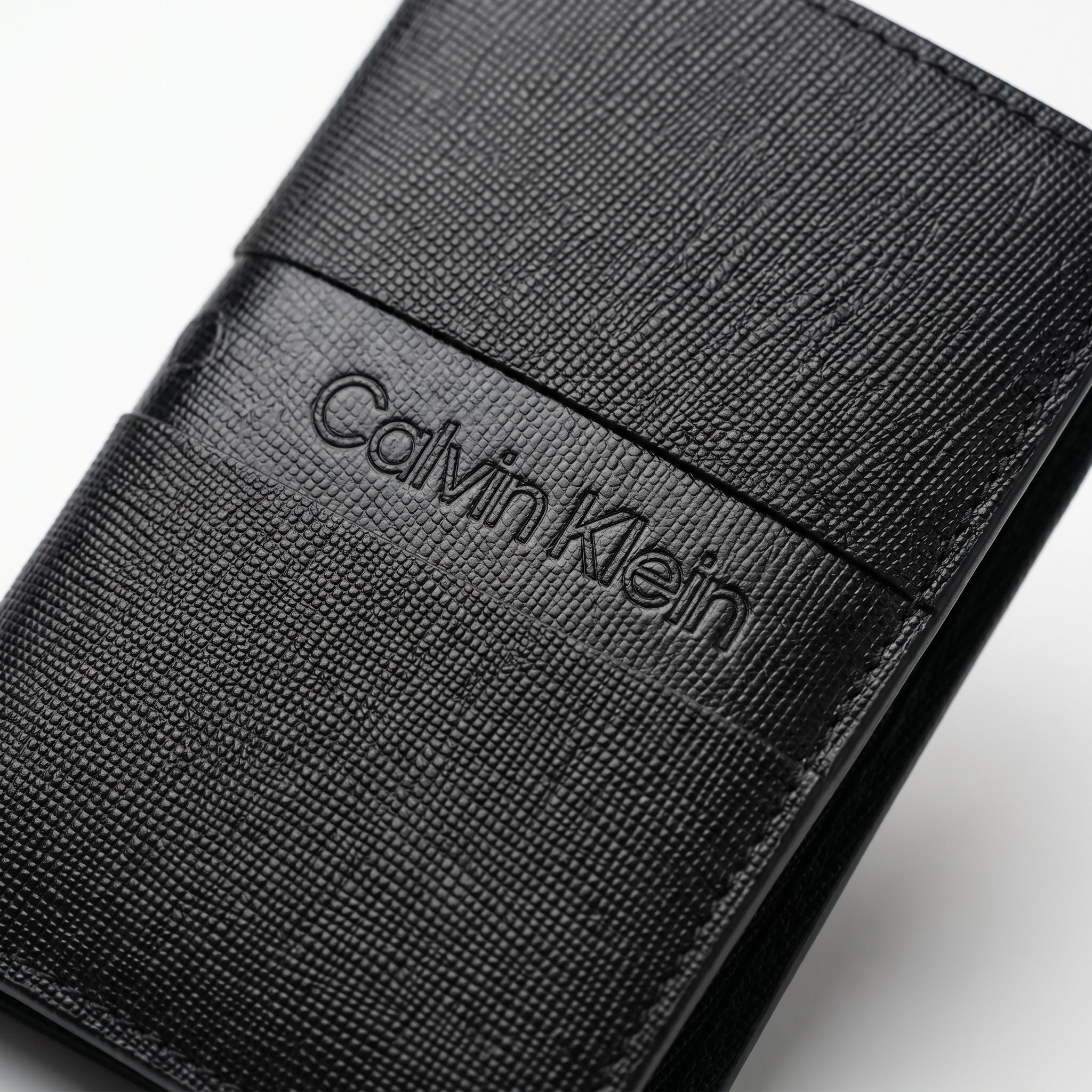 Macro close-up view showing the high-quality saffiano leather texture and precision engraved Calvin Klein center logo