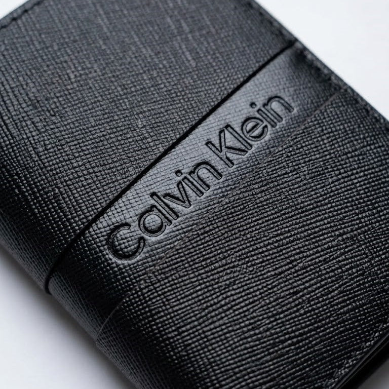 Macro close-up view showing the high-quality saffiano leather texture and precision engraved Calvin Klein center logo