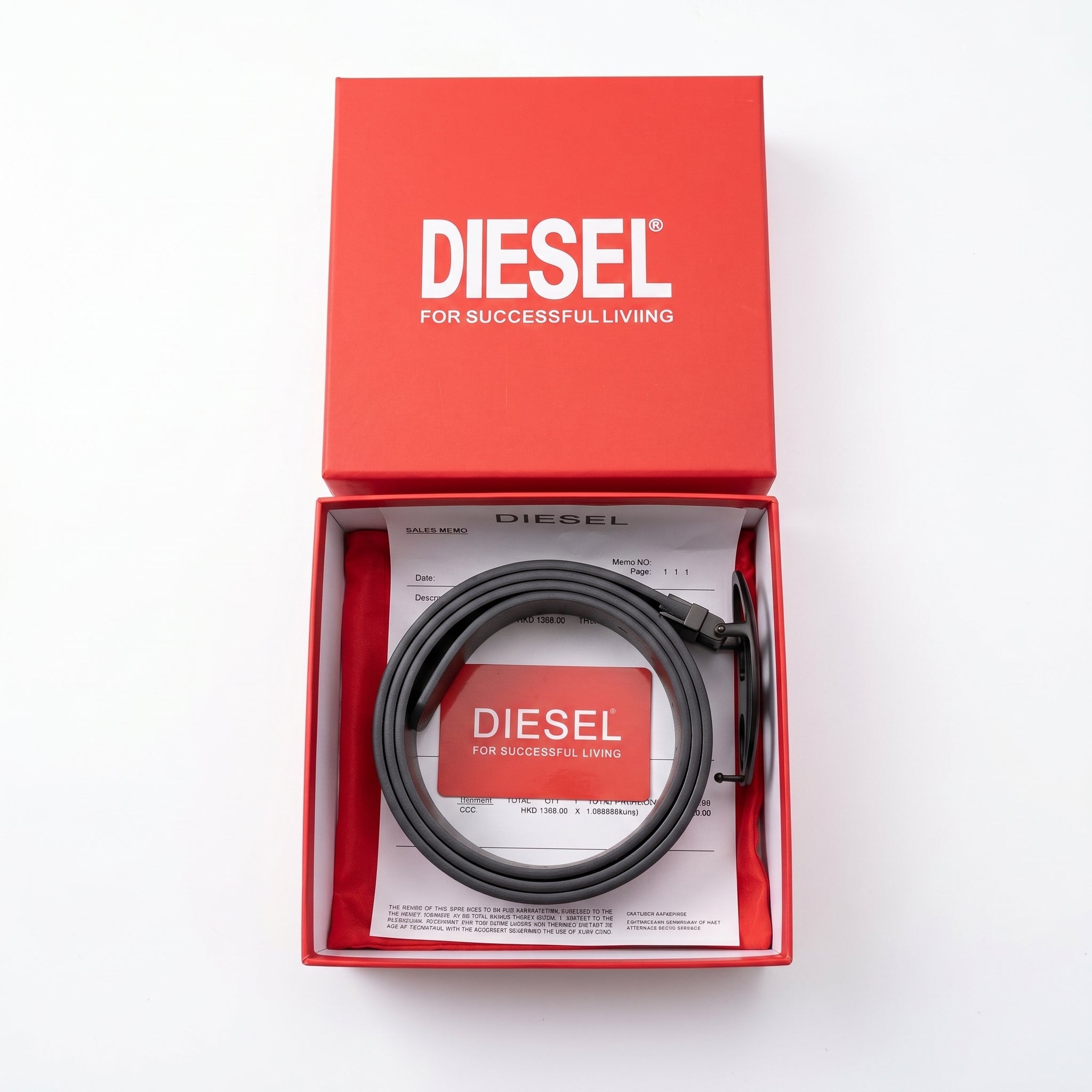 Top-down style studio product photography of the Diesel mirror original black leather belt neatly rolled inside its open custom red branded gift box with papers