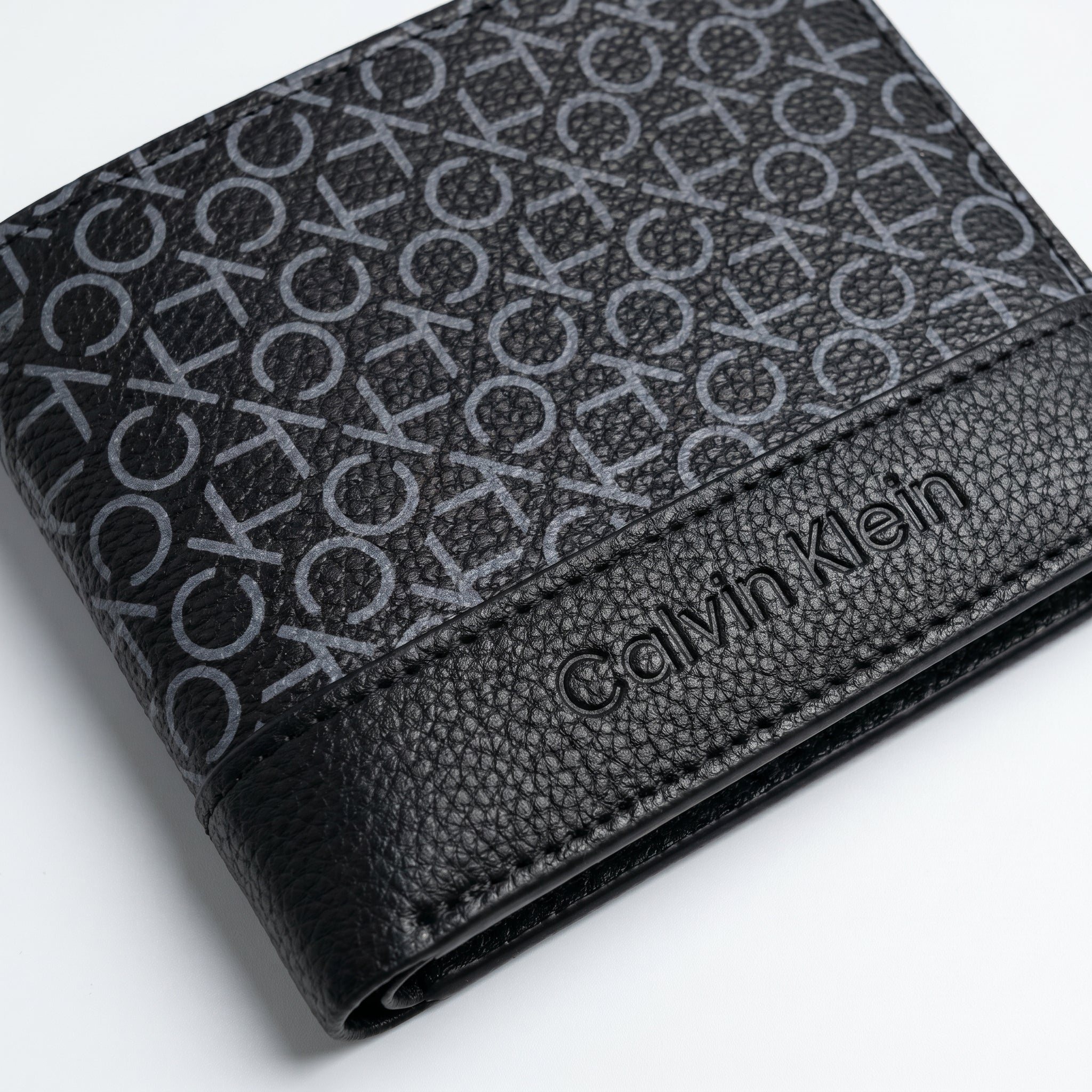 Professional angled studio photograph of the sleek Calvin Klein mirror original smooth black leather trifold wallet