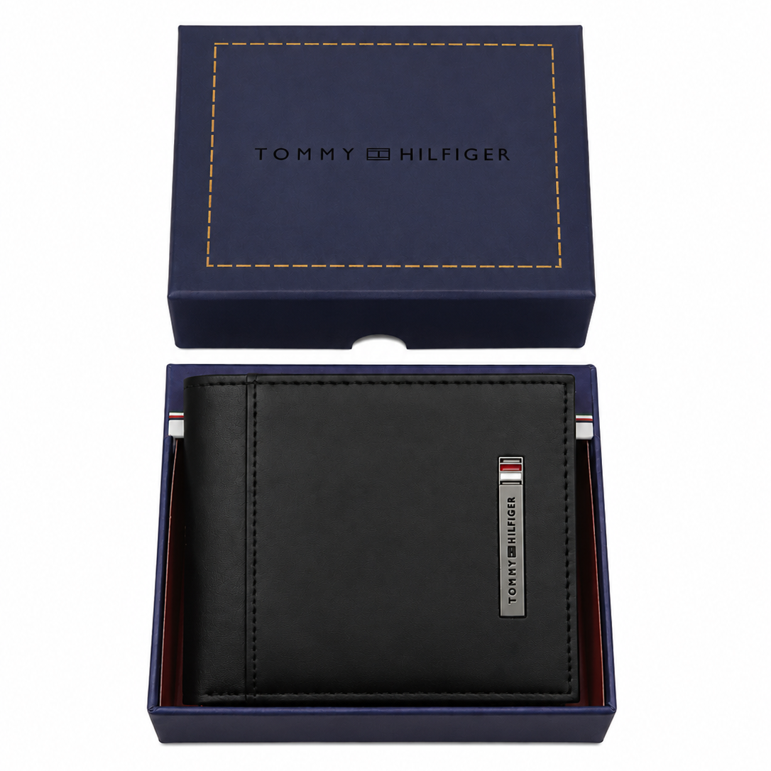 Top-down studio photograph of the Tommy Hilfiger black leather wallet with metal bar logo neatly placed inside its navy gift box