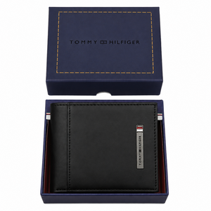 Top-down studio photograph of the Tommy Hilfiger black leather wallet with metal bar logo neatly placed inside its navy gift box