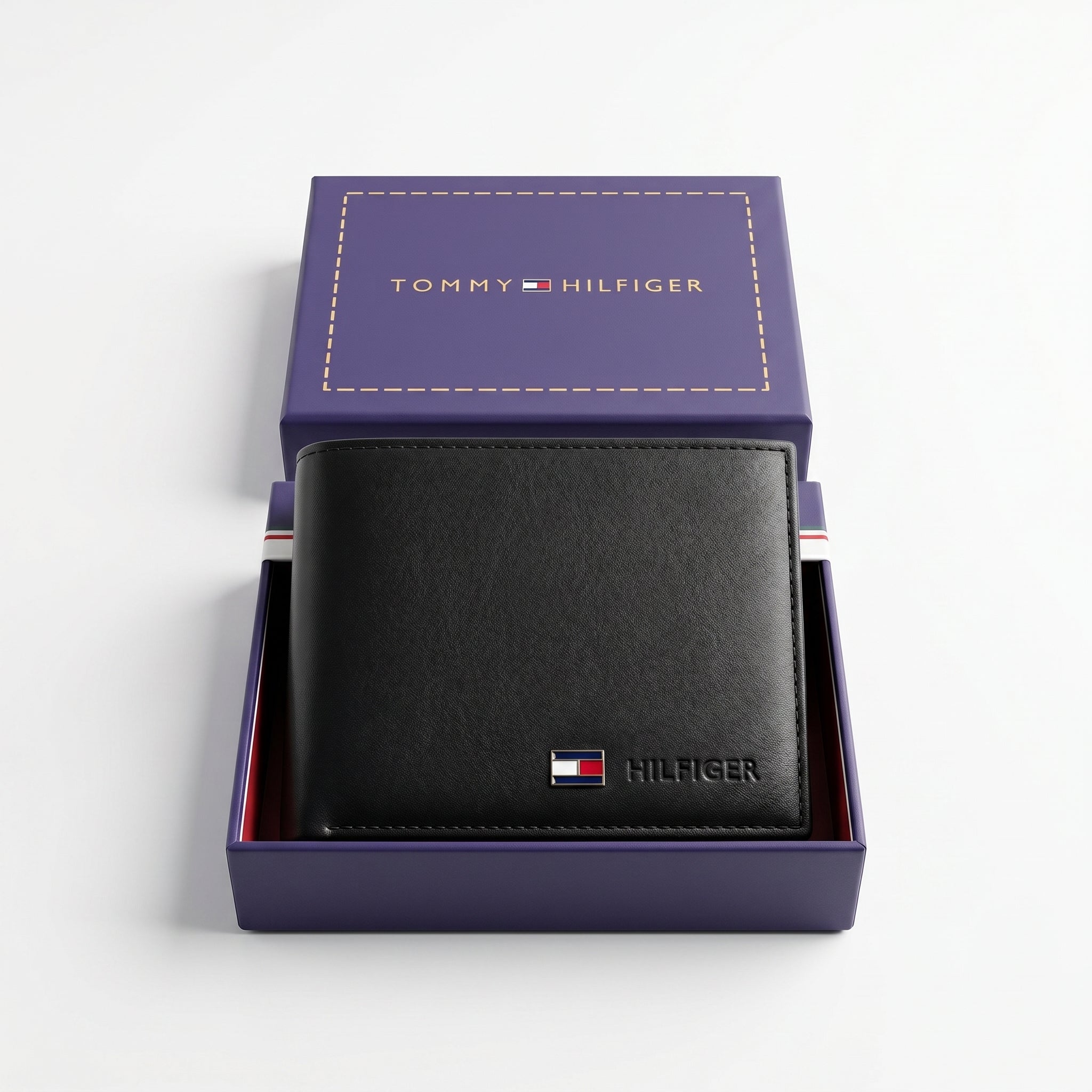 Top-down studio photograph of the Tommy Hilfiger smooth black leather wallet neatly placed inside its open premium navy gift box