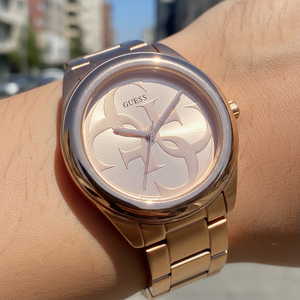 Close up shot of Guess W1082L3 watch on wrist showing the rose gold sunray dial and logo details