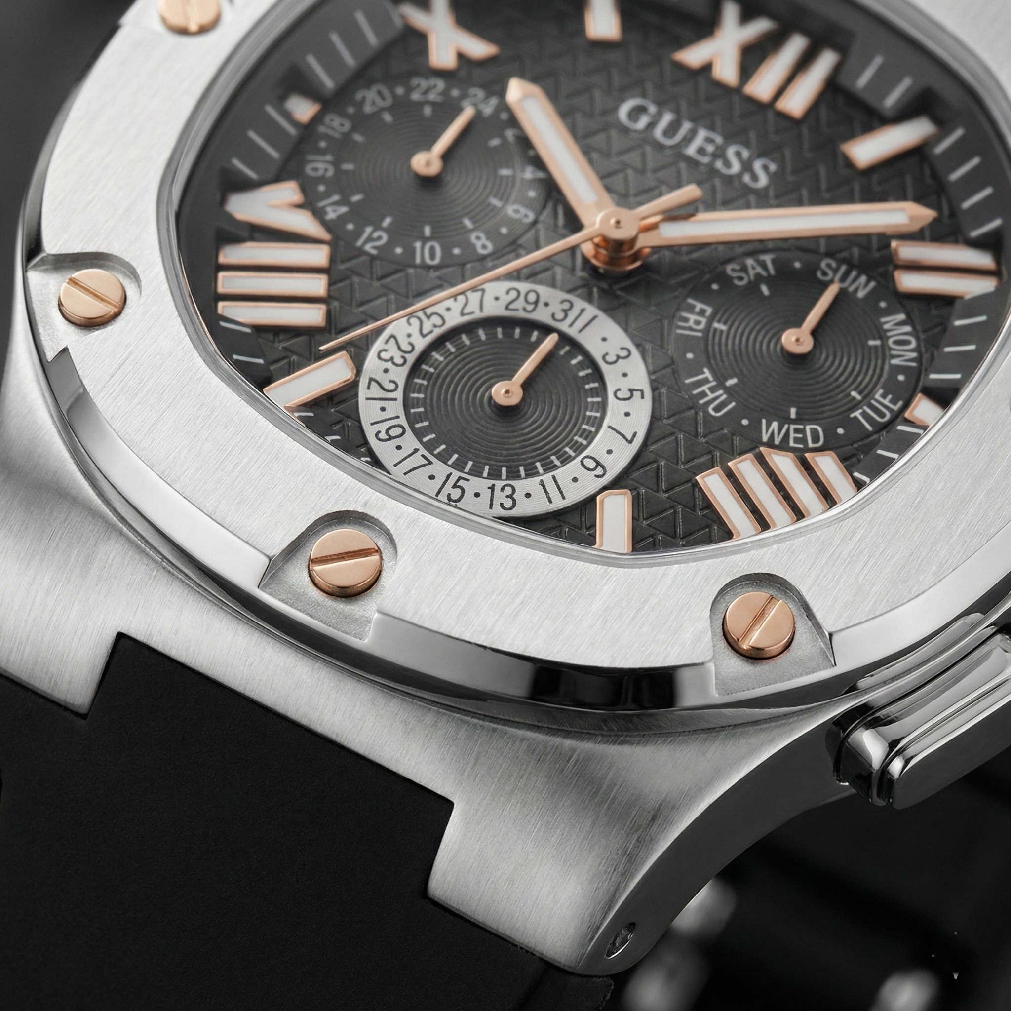 Close up shot of Guess GW0571G1 watch on wrist showing the black textured dial and golden bezel screws