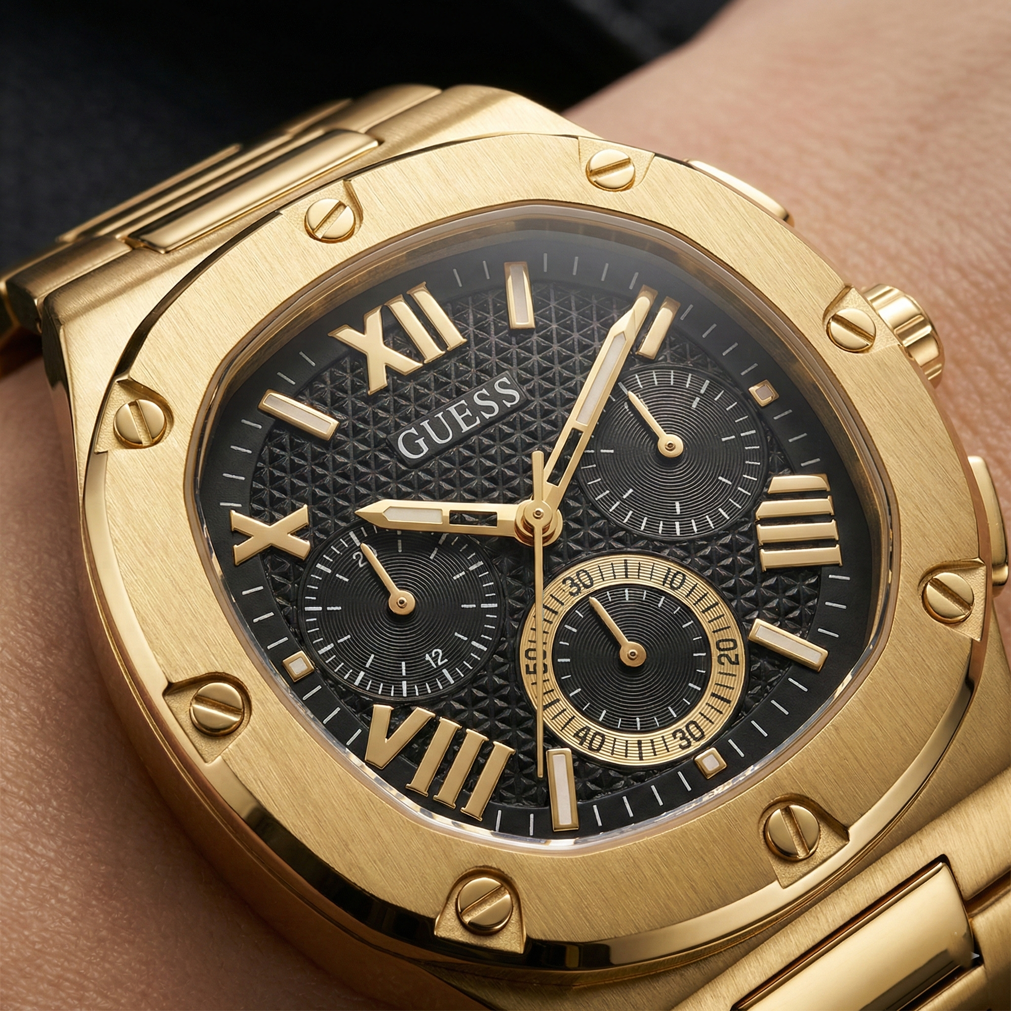 Close up shot of Guess GW0572G2 watch on wrist showing the black textured dial and gold bezel screws