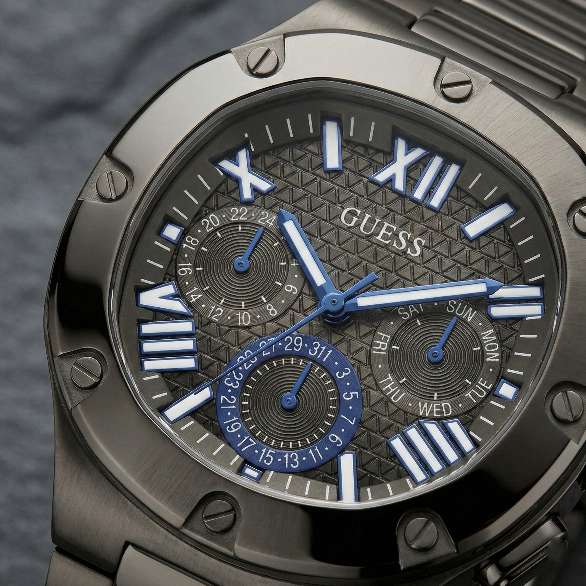 Close-up of the textured grey multifunction dial with blue hands on Guess GW0572G5