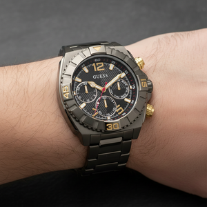 Close up shot of Guess GW0800G2 watch on wrist highlighting the black dial with gold markers and red accents