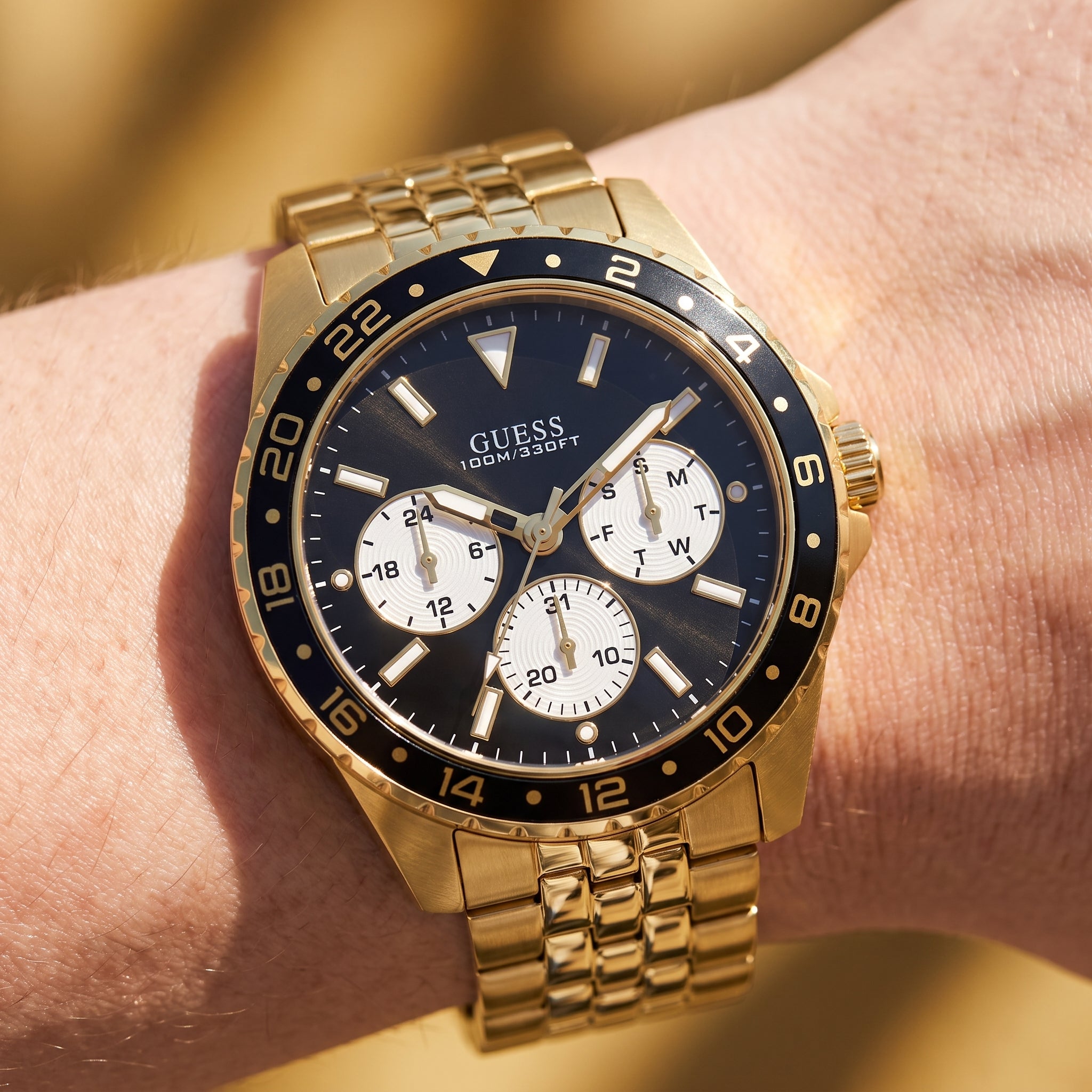 Wrist shot of Guess W1107G4 watch showing the gold metal band