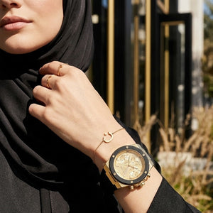 Elegant woman wearing Guess athena  GW0030L2 women's quartz battery watch with gold case and luxury black rubber strap