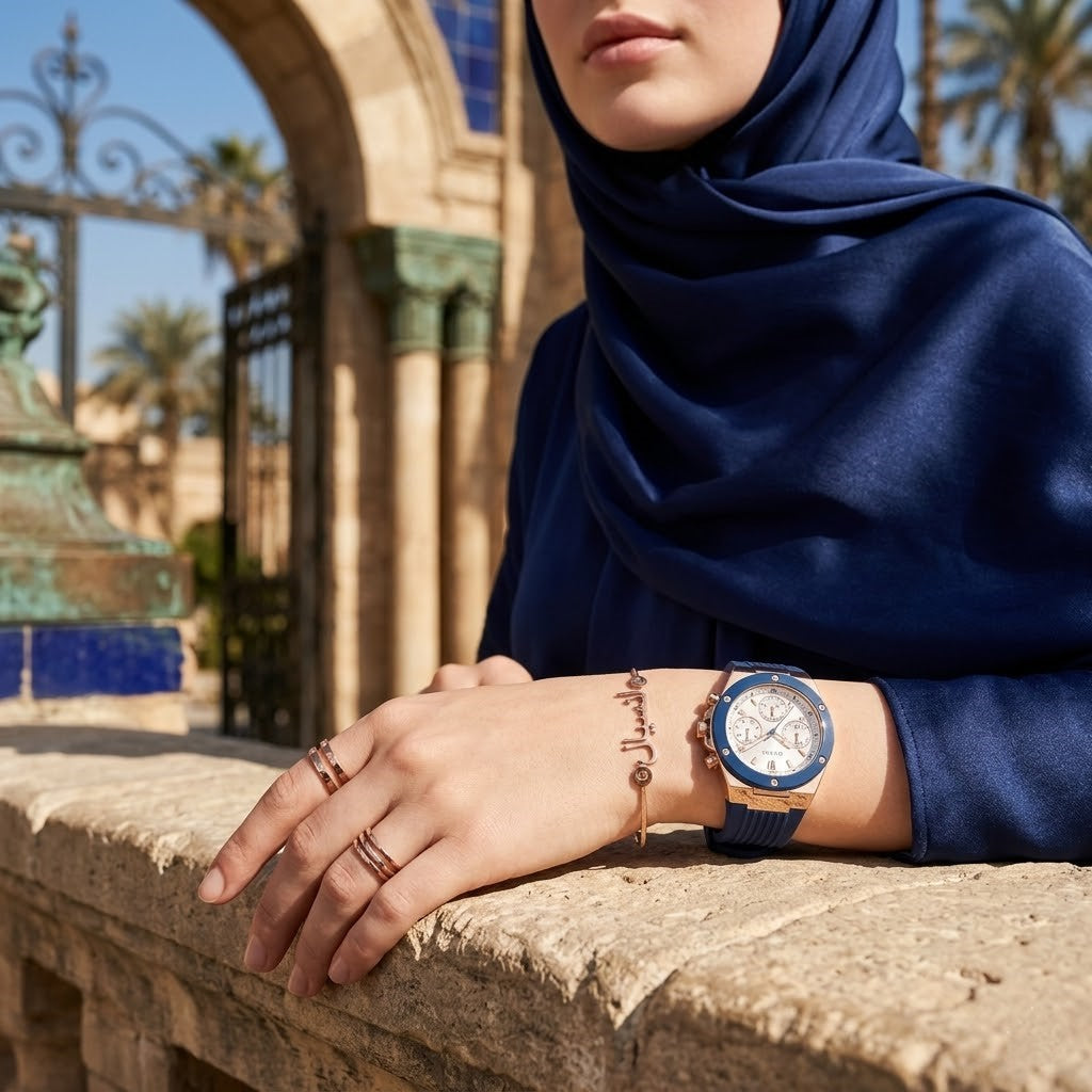 Elegant woman wearing Guess Athena GW0030L5 women's quartz battery watch with rose gold case and luxury blue rubber strap