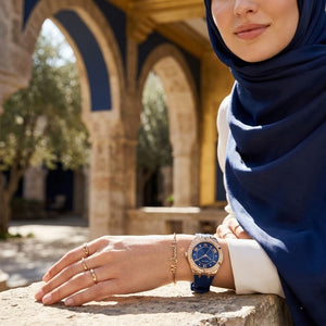 Elegant woman wearing Guess Cosmo GW0034L4 women's quartz battery watch with gold case and luxury blue rubber strap