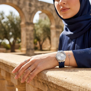 Elegant woman wearing Guess Cosmo GW0034L5 women's quartz battery watch with silver case and luxury blue rubber strap