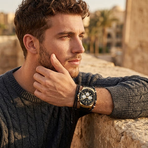 Elegant man wearing Guess Poseidon GW0057G1 men's quartz battery watch with gold case and luxury black rubber strap