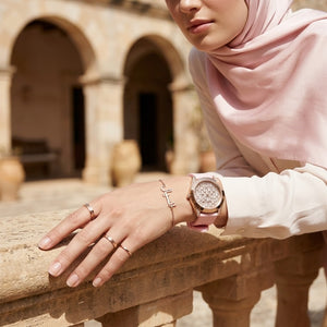 Elegant woman wearing Guess Lady Frontier GW0109L2 women's quartz battery watch with rose gold case and luxury pink rubber strap