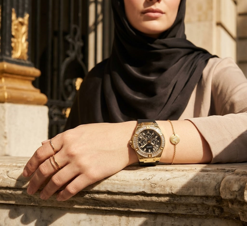 Elegant woman wearing Guess Venus GW0118L1 women's quartz battery watch with gold case and luxury black rubber strap