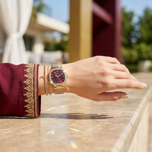 Close up of Guess Tapestry GW0354L4 women's quartz battery watch on wrist showing burgundy dial and luxury crystal square bezel