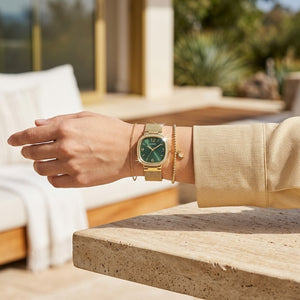 Close up of Guess GW0354L5 women's quartz battery watch on wrist showing green dial and luxury crystal square bezel