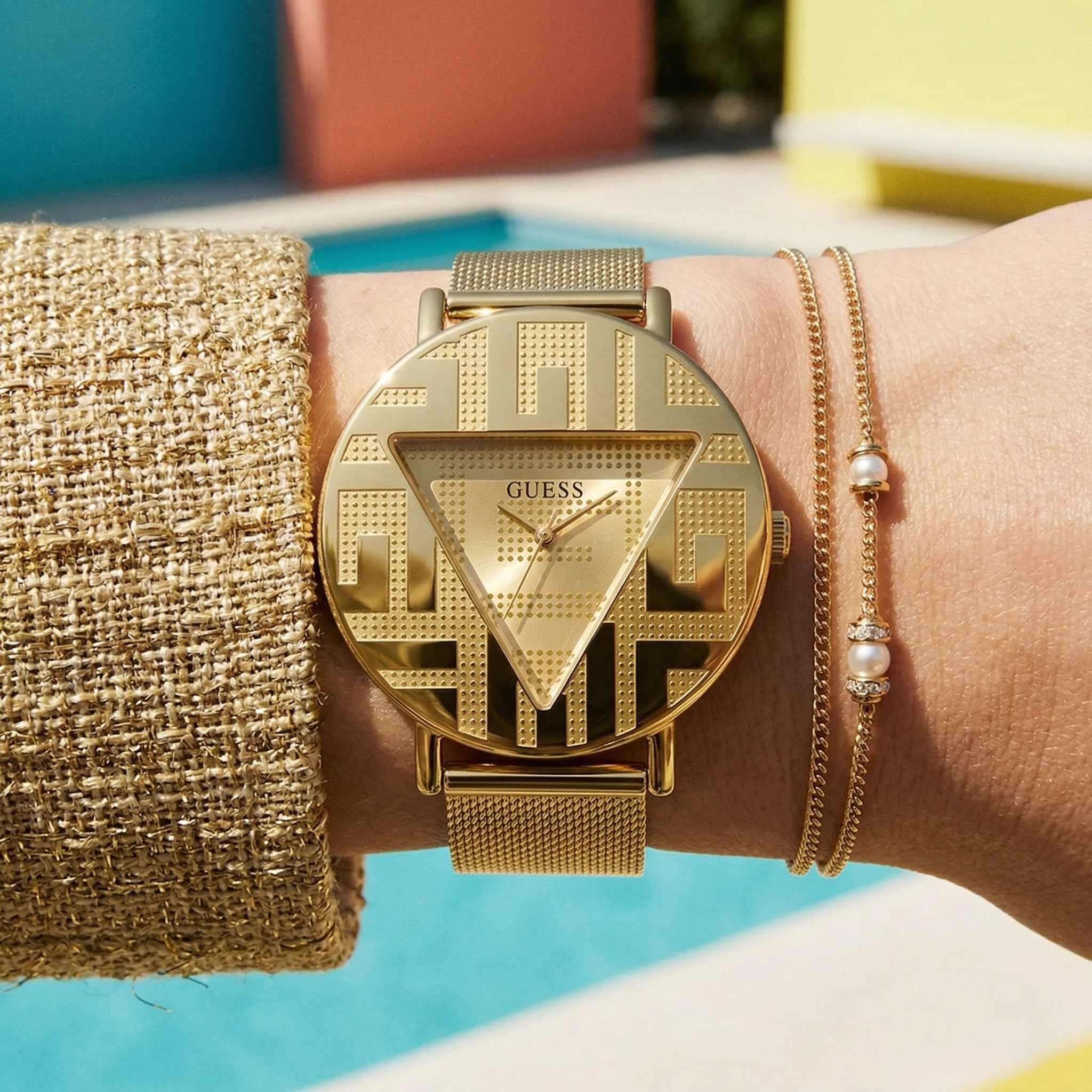 Close up of Guess Iconic GW0527L2 women's quartz battery watch on wrist showing clean gold dial and iconic brand logo
