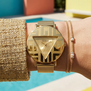 Close up of Guess Iconic GW0527L2 women's quartz battery watch on wrist showing clean gold dial and iconic brand logo