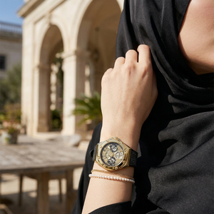 Elegant woman wearing Guess Asteria GW0620L2 women's quartz battery watch with gold case and luxury black rubber strap