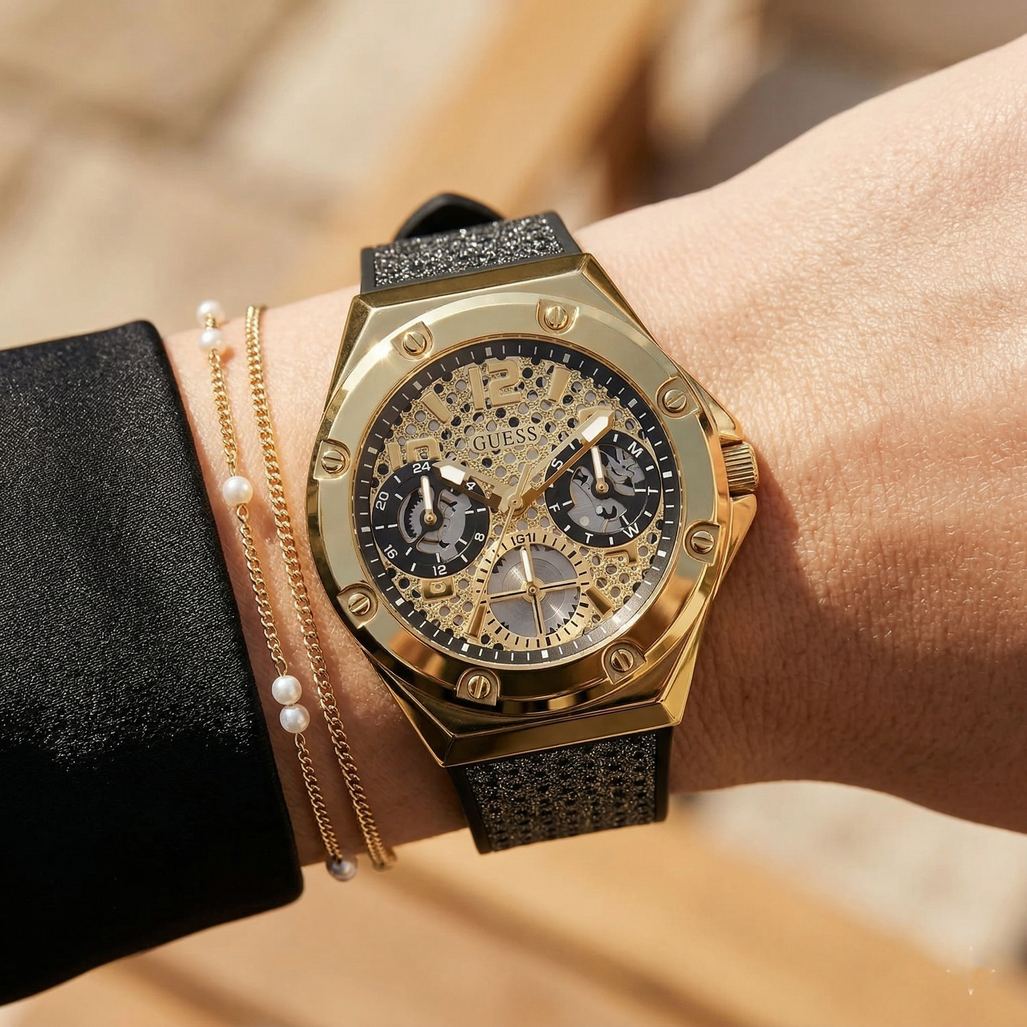 Close up of Guess Asteria GW0620L2 women's quartz battery watch on wrist showing intricate cut-out dial and luxury gold bezel