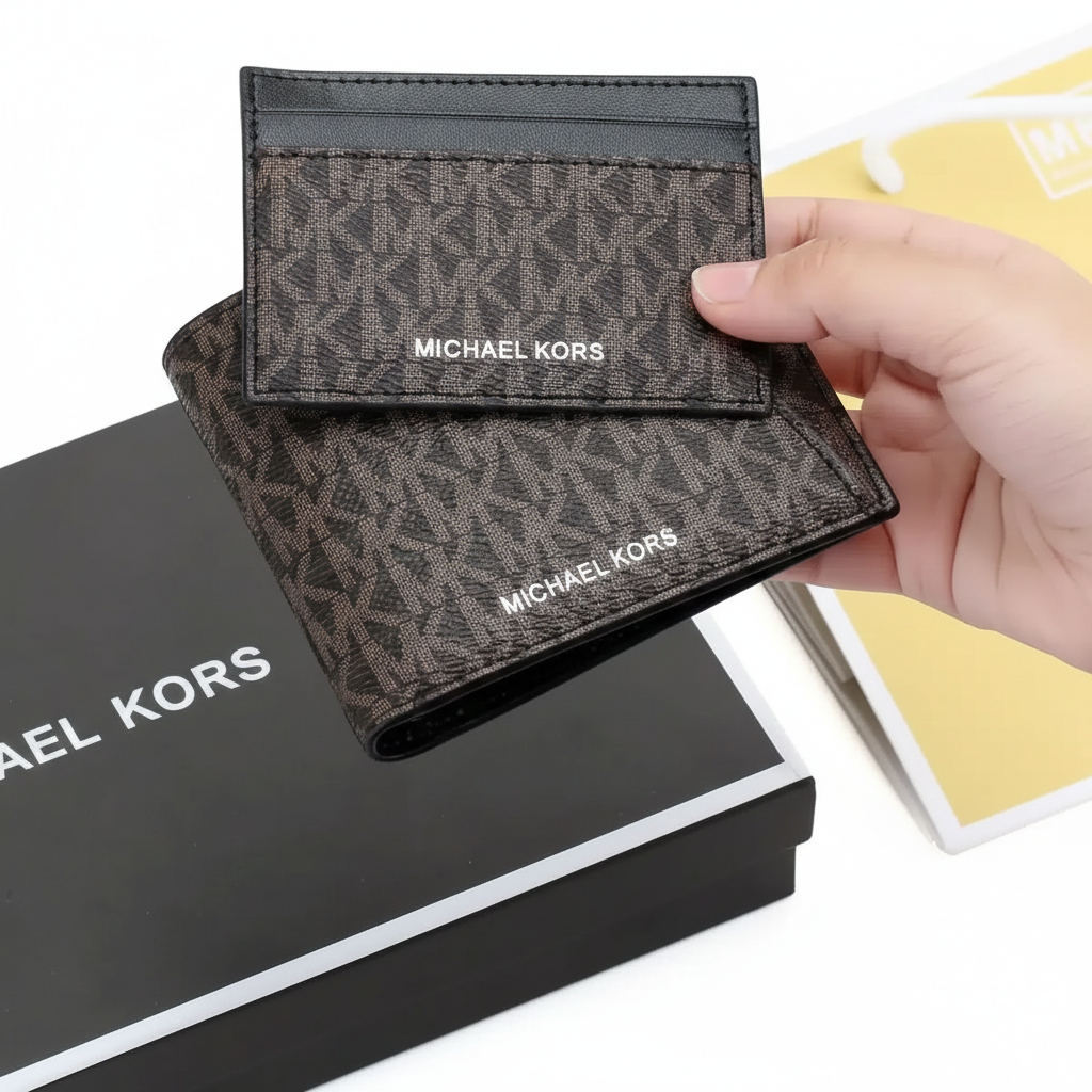 Hand holding a Michael Kors men's brown MK patterned wallet and cardholder set above its original black gift box and branded shopping bag`