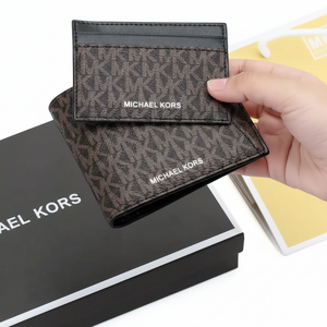 Hand holding a Michael Kors men's brown MK patterned wallet and cardholder set above its original black gift box and branded shopping bag`