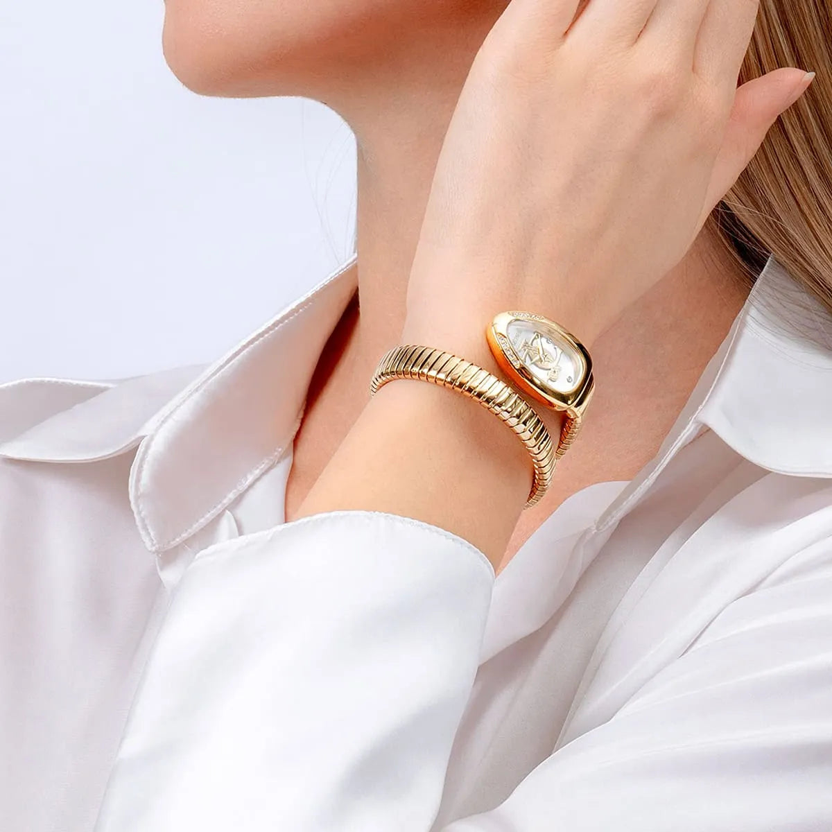 Gold bracelet with a large gemstone on a person wearing a white shirt.