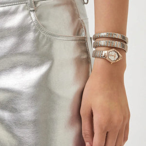 Close-up of a hand wearing multiple bracelets on a plain background