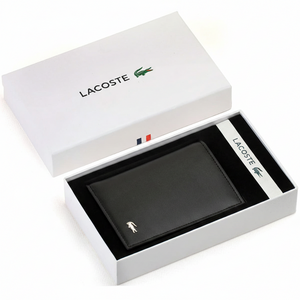 Top-down view of a Lacoste men's black smooth leather bifold wallet with a silver crocodile logo, presented inside its original white branded gift box