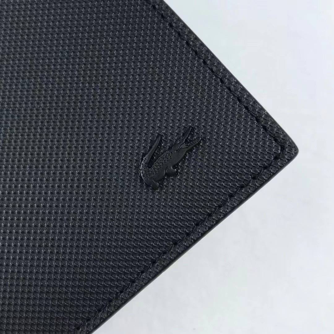 Close up detail of black metal Lacoste crocodile logo on signature Petit Piqué textured leather