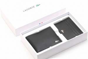 Angled perspective of a Lacoste men's black leather wallet and cardholder set securely presented inside its original white branded gift box