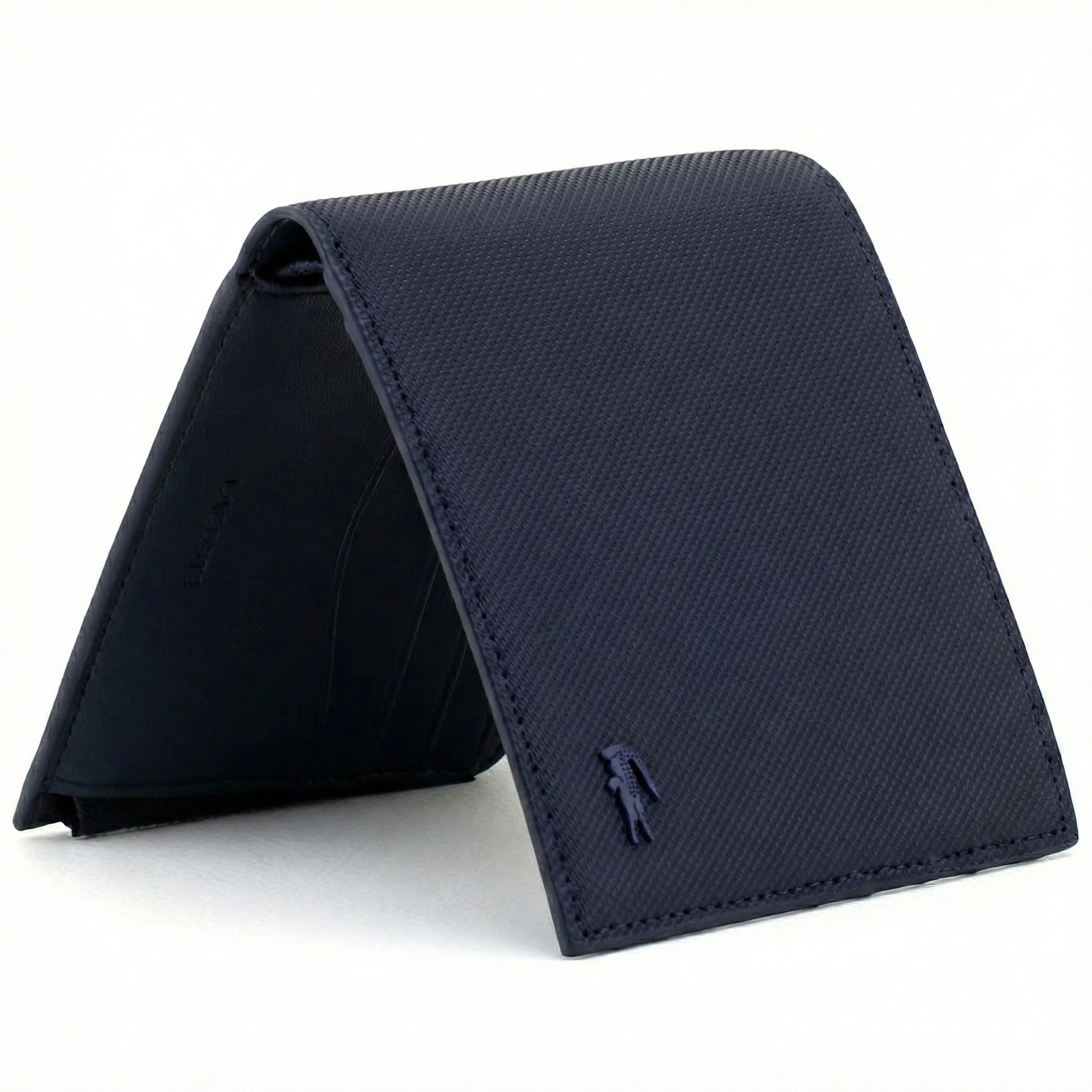 Perspective view of a standing semi-open Lacoste men's navy blue textured leather bifold wallet showcasing the matching tonal navy crocodile logo
